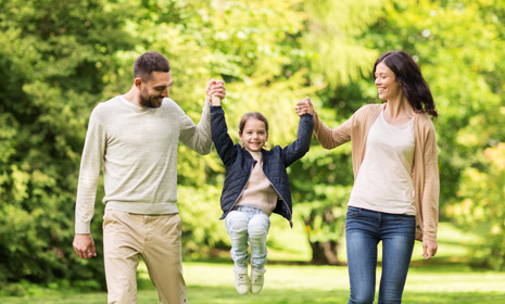 Parents swinging child while walking outdoors