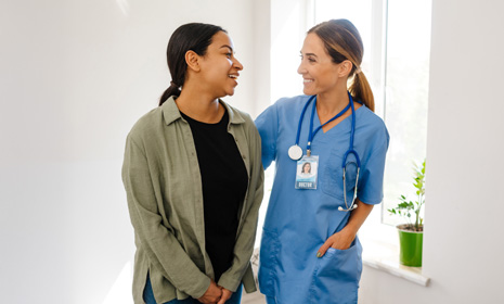 Nurse supporting patient in clinic hallway