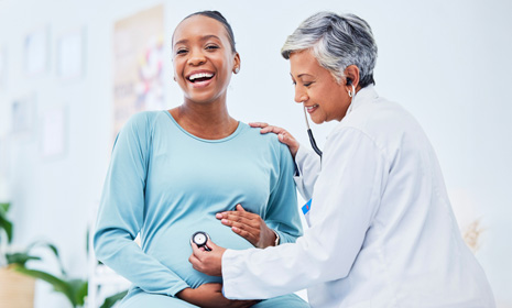 Doctor using stethoscope on pregnant patient
