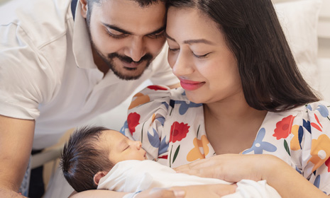Parents holding newborn in hospital room