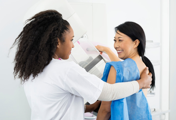 Technician assisting patient during mammogram exam